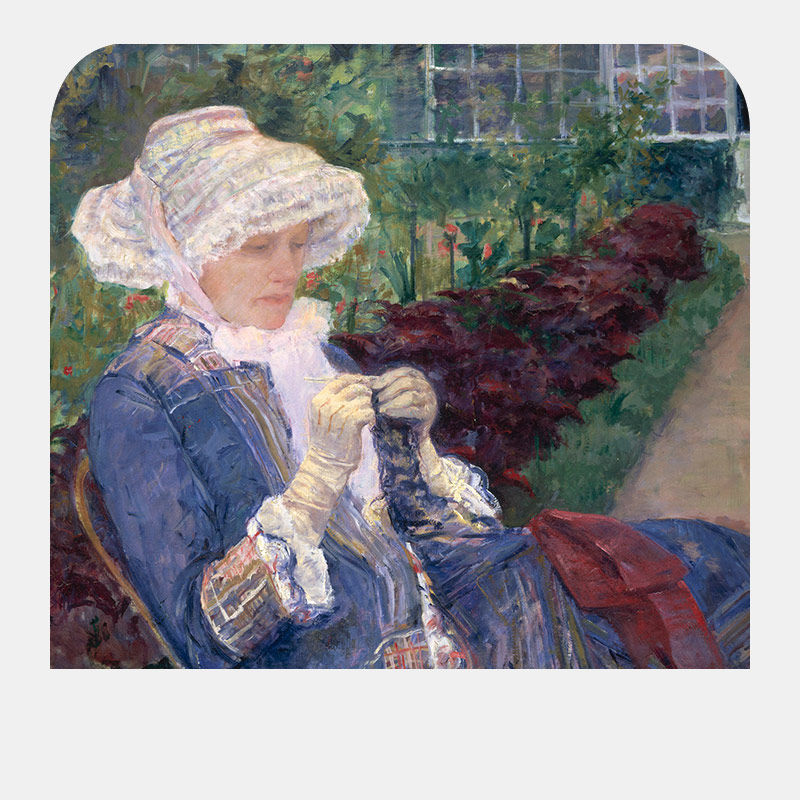 A woman with a flared white cap and a blue dress sits on a bench sowing blue fabric.